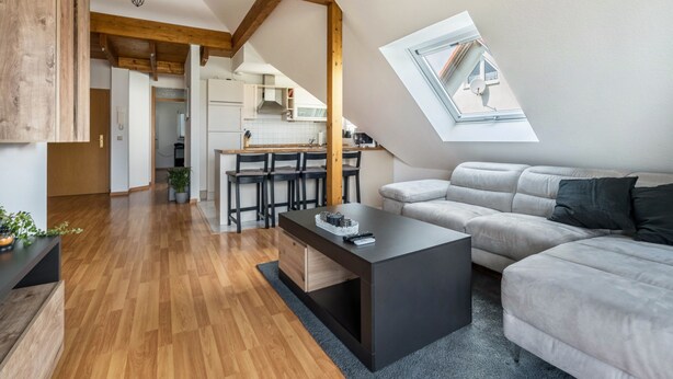 Un loft moderno con comedor, cocina y un amplio tragaluz.