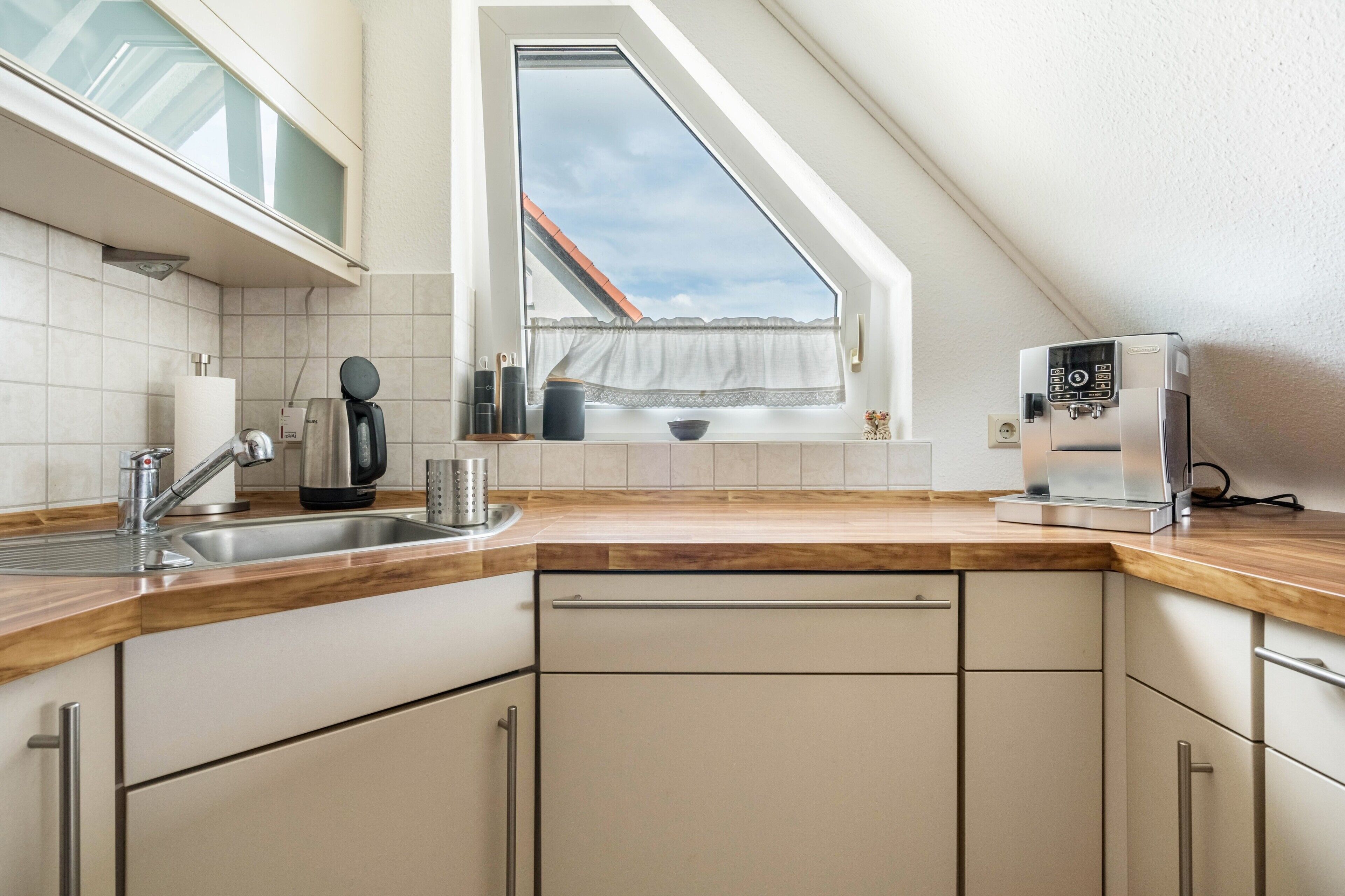 Eine Küche mit Fenster, einer Kaffeemaschine und einem Spülbecken.