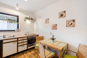 Cozinha compacta com janela, mesa de jantar com cadeiras e decoração temática de café nas paredes.