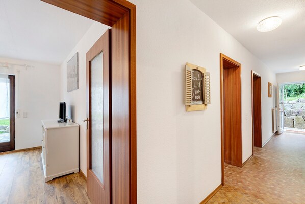 A hallway with wooden doors, a white cabinet, and a chalkboard with text. - Apartment "Murgperle" with Mountain View, Private Terrace & Wi-Fi (Gernsbach)