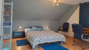 Une chambre à coucher comprenant un lit, un bureau, une chaise, une échelle et un luminaire fixé au plafond.
