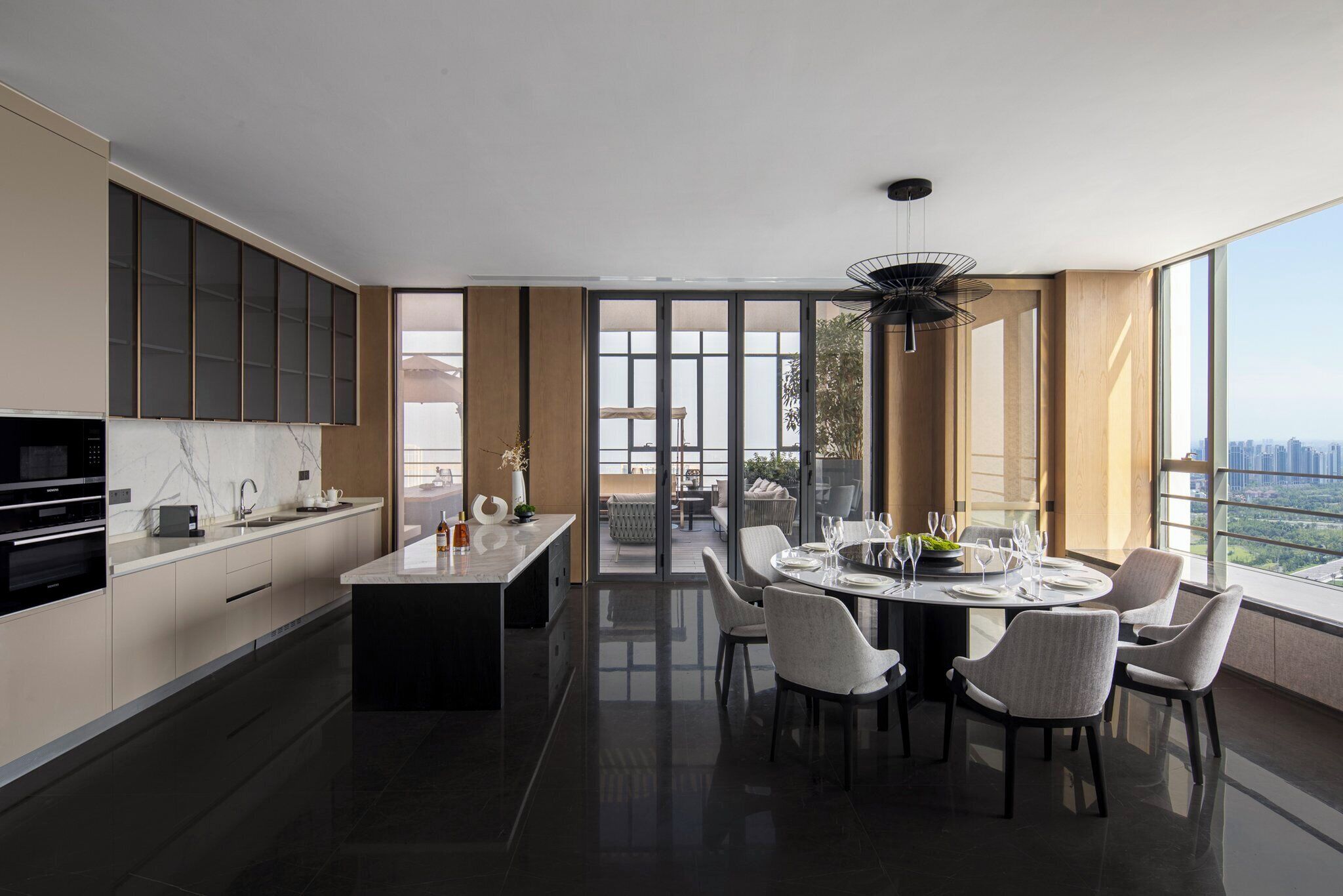 A modern kitchen with a dining area, large windows, and a view of the city.