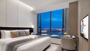 A modern hotel room with a large bed, a desk, and a view of the cityscape through large windows. - Ascott Tianfu CBD Chengdu (Chengdu)