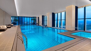 A modern indoor swimming pool with clear blue water, large windows, and a view of the cityscape. - Ascott Tianfu CBD Chengdu (Chengdu)
