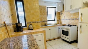 A kitchen with granite countertops, white cabinets, a stove, and a refrigerator. - Charming Getaway in Casablanca Maroc, Cozy Home with Thoughtful Amenities (Casablanca)