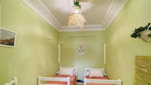 A room with two single beds, a chair, a hanging light fixture, and a wall-mounted decoration. - Charming Getaway in Casablanca Maroc, Cozy Home with Thoughtful Amenities (Casablanca)