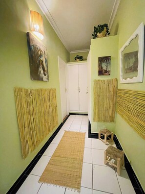Stylish hallway with wall art, a woven rug, and a wooden stool.