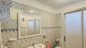 A bathroom with a tiled backsplash, a sink, a toilet, a mirror, and a door. - Coquet Appartement À Casablanca (Casablanca)