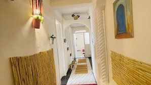 A hotel hallway with a red carpet, white walls, and a blue door at the end. - Coquet Appartement À Casablanca (Casablanca)