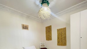 A bedroom with a bed, a nightstand, a wardrobe, and a hanging light fixture. - Coquet Appartement À Casablanca (Casablanca)