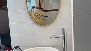 A bathroom with a white sink, a gold-framed mirror, and a modern faucet.