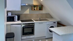 A compact kitchen with a skylight, built-in appliances, and a small laundry area.