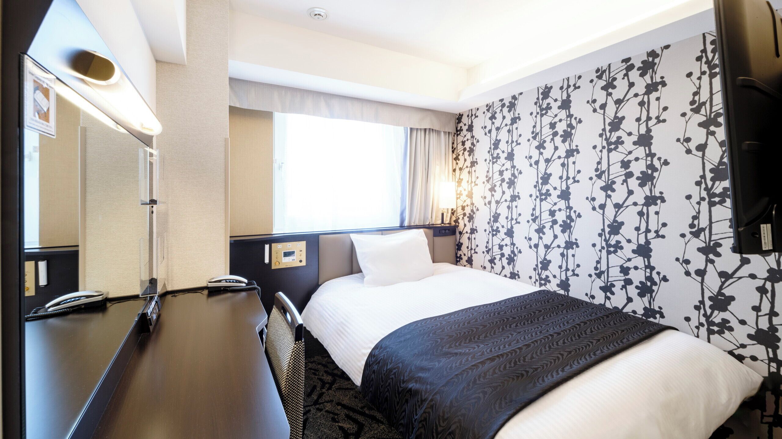 Ein Hotelzimmer mit Bett, Schreibtisch, Telefon und Fernseher.