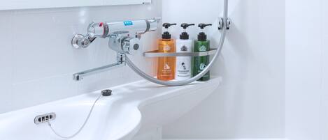 Une salle de bain avec un lavabo blanc, un miroir et une étagère contenant des articles de toilette.