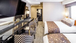 Ein Hotelzimmer mit einem großen Bett, einem Esstisch mit Stühlen, einer kleinen Küchenzeile und einem großen Spiegel.