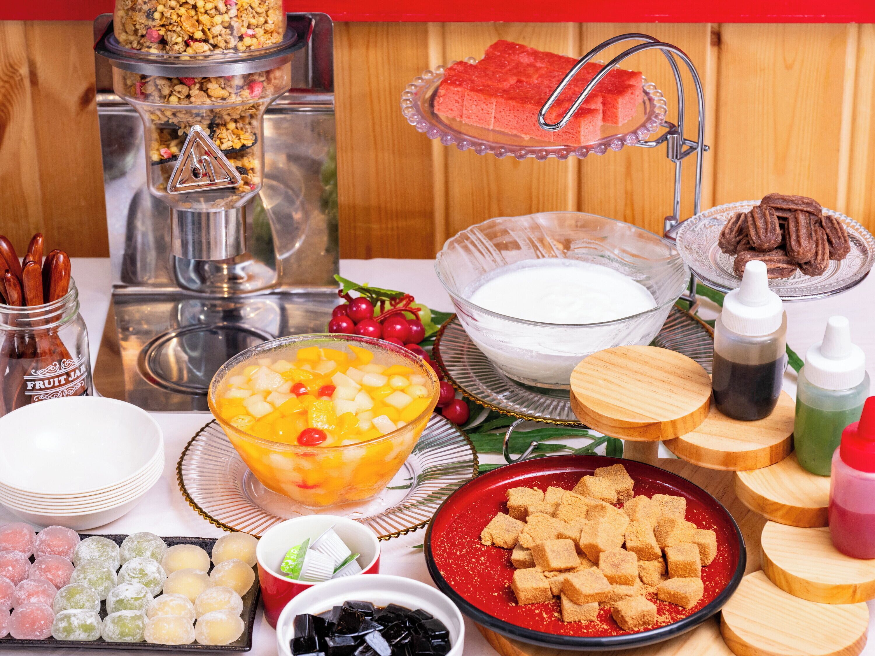 A buffet table with various food items including fruit, desserts, and beverages.