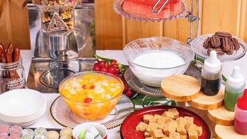 A buffet table with various food items including fruit, desserts, and beverages.