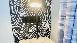 A bathroom with a modern design, featuring a wall-mounted light fixture, a white pedestal sink, and a patterned wallpaper. - Ferienwohnung "ME 7" (Mettmann)