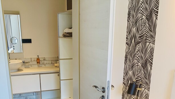 A bedroom with a bed, a bedside table, and a wardrobe. - Ferienwohnung "ME 7" (Mettmann)
