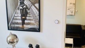 A framed artwork of a woman on stairs, a globe, and two figurines on a white cabinet. - Ferienwohnung "ME 7" (Mettmann)