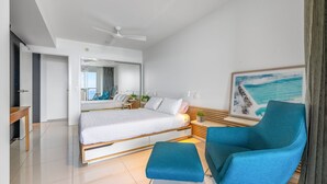 A modern bedroom with a bed, a blue armchair, a side table, and a large window with a view. - Kings Edge Unit 4 Kings Beach QLD (Kings Beach)