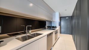 A modern kitchen with a large island, stainless steel appliances, and a dark backsplash. - Kings Edge Unit 4 Kings Beach QLD (Kings Beach)