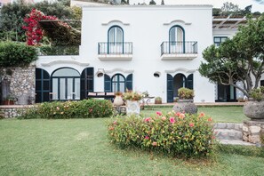 A two-story building with a stone facade, arched windows, and a balcony with a metal railing. - Villa Michika by Elite Villas (Capri)