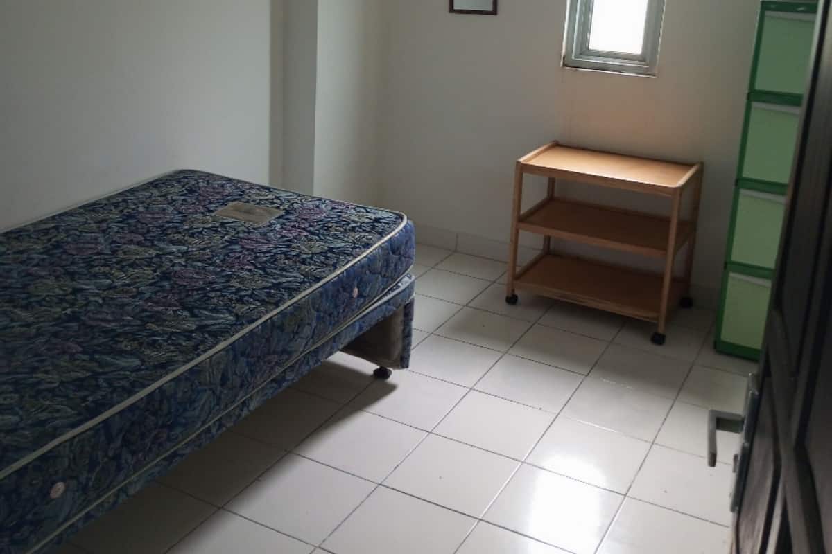 Ein Zimmer mit einem Bett, einem kleinen Tisch und einem Fenster.