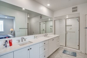 Un baño moderno con un espejo grande, dos lavamanos, una bañera y una ducha a ras de suelo.