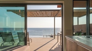 A modern room with a large glass door leading to a balcony overlooking the ocean. - Casa Tarrha - Beachside Retreat with Private Heated Pool (Chania Town  Livadia)