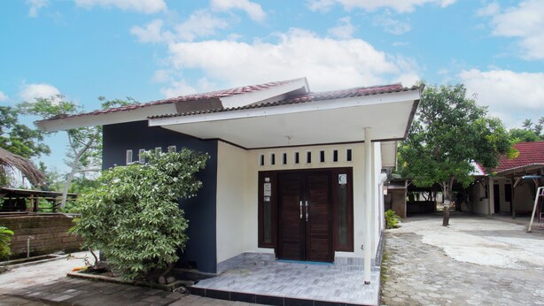 A two-story building with a dark facade and a tiled roof. - SPOT ON 93724 Songgong Homestay (Mertak)