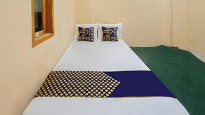 A single bed with two pillows, a blue and yellow polka dot blanket, and a green carpeted floor. - SPOT ON 93724 Songgong Homestay (Mertak)