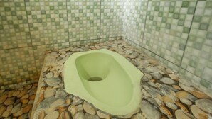 A bathroom with a stone floor and a green toilet. - SPOT ON 93724 Songgong Homestay (Mertak)