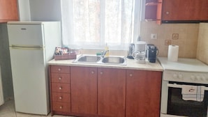 Cocina compacta con refrigerador, pileta, cafetera y horno.