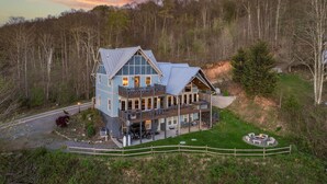 Een groot, ruim vakantiehuis met twee verdiepingen, met een opvallend balkon en een vuurplaats, omgeven door beboste heuvels.