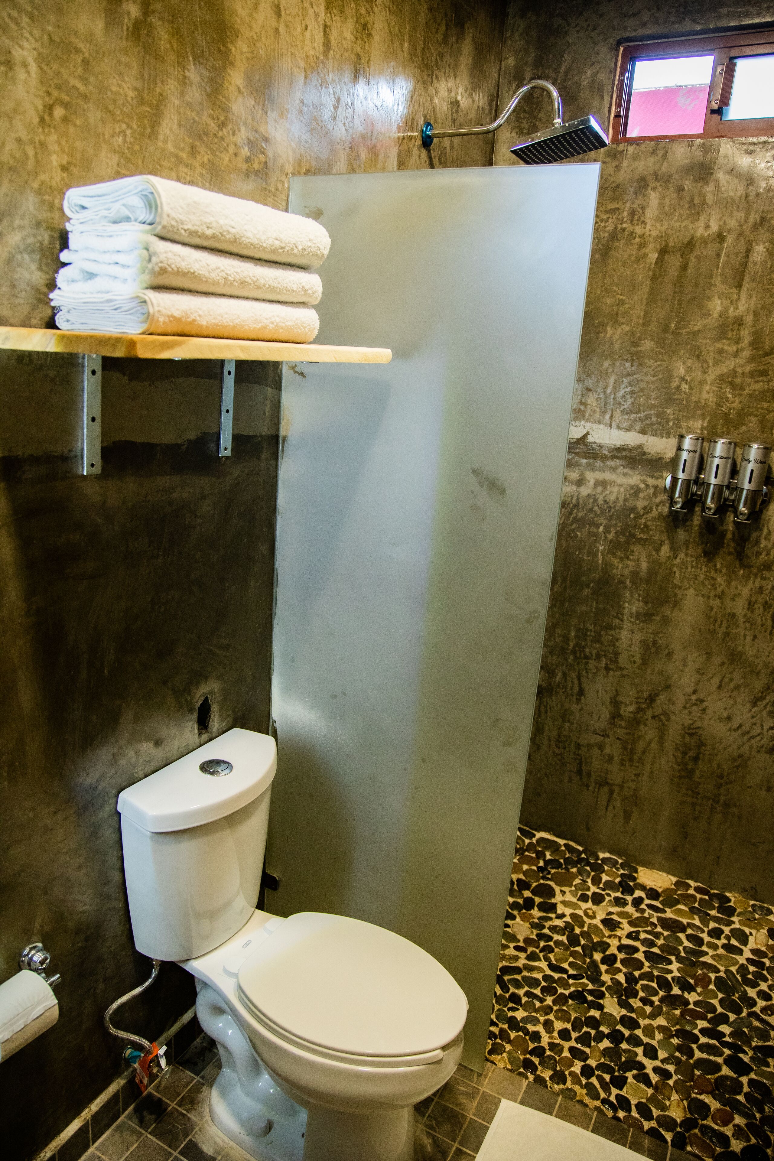 Een badkamer met toilet, douche en betegelde vloer.