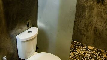 Een badkamer met toilet, douche en betegelde vloer.