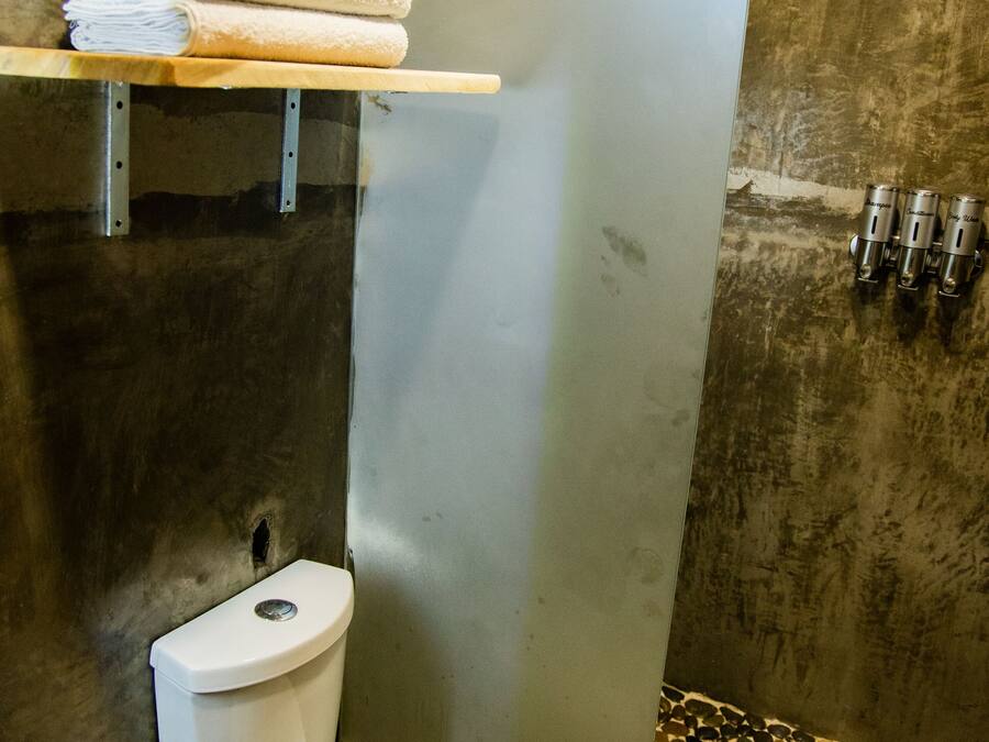 Een badkamer met toilet, douche en betegelde vloer.