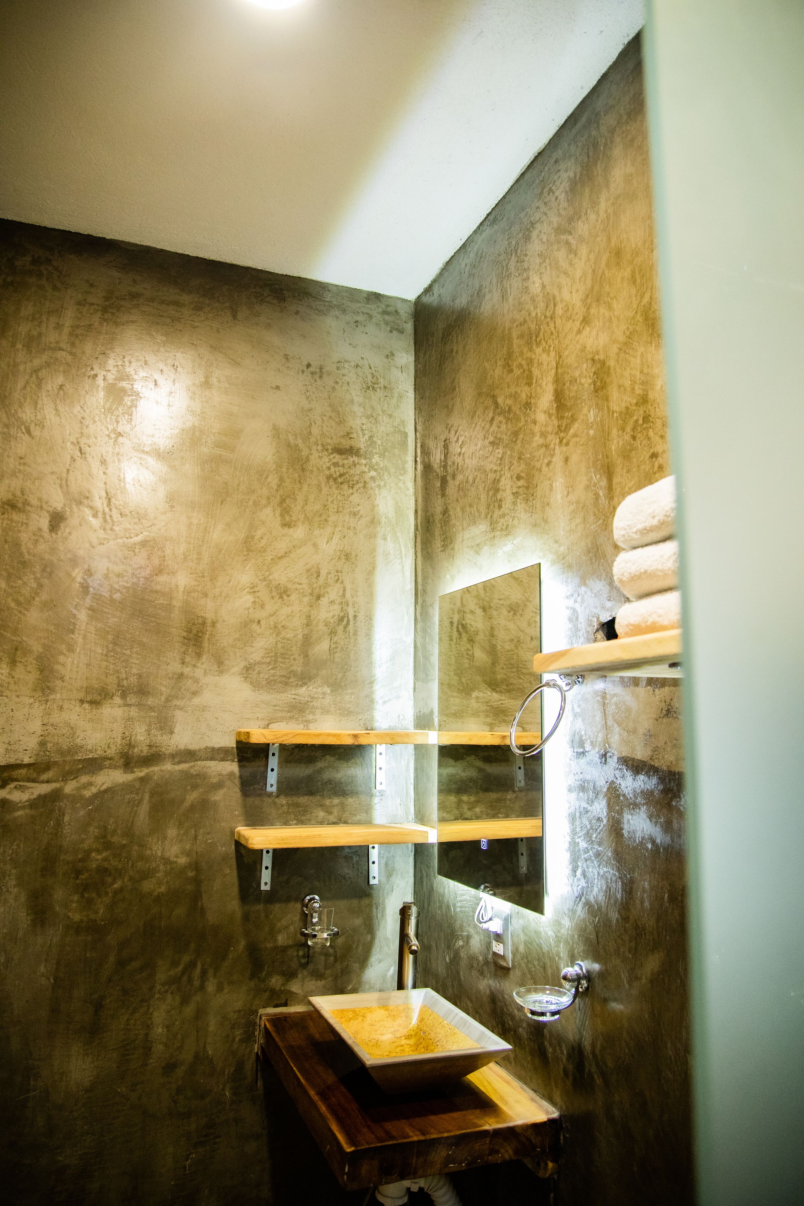 A bathroom with a wooden vanity, a sink, a mirror, and a towel rack.