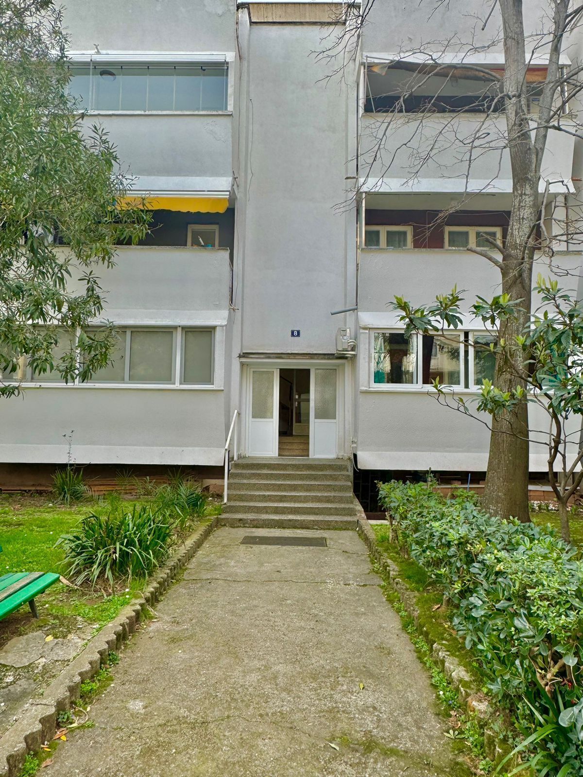 A multi-story building with a central entrance and a staircase leading to the ground floor.