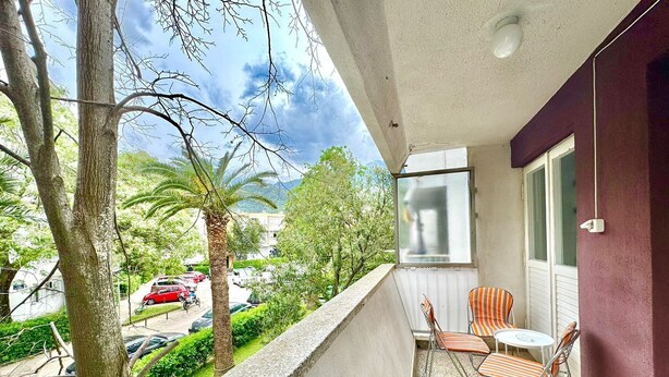 A balcony with a view of a street, a palm tree, and a parked car. - Family two bedroom apartment Slavia (Budva)
