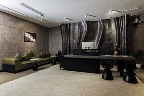 A modern reception area with a sofa, check-in counter, and a large window. - The Concept Hotel HCMC - City Center (Ho Chi Minh City)