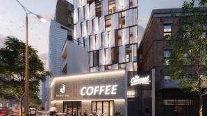 Un hotel moderno con un cartello ben visibile che riporta 'The Concept Hotel', un locale 'Coffee' a livello strada e una facciata in vetro con numerose finestre.