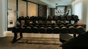 Una palestra con rastrelliera per manubri a parete e un cartello luminoso al neon con la scritta "GYM".