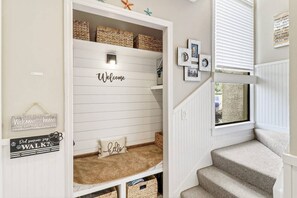 A home entryway with a 'Welcome' sign, a 'Did someone say WALK?' sign, and a 'Welcome to home' sign with a dog kiss.