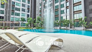 A modern hotel with a swimming pool, lounge chairs, and a fountain. - Cubic Botanical Premium Suites atBangsar (Kuala Lumpur)