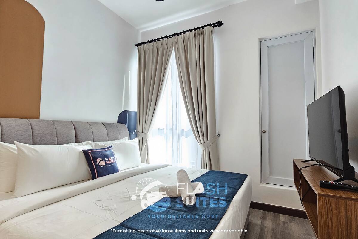 A hotel room with a bed, a television, and a window with curtains.