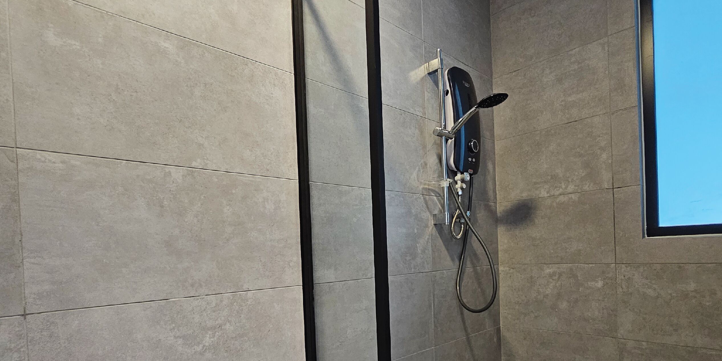 A shower with a handheld showerhead and a handheld scrubber mounted on the wall.