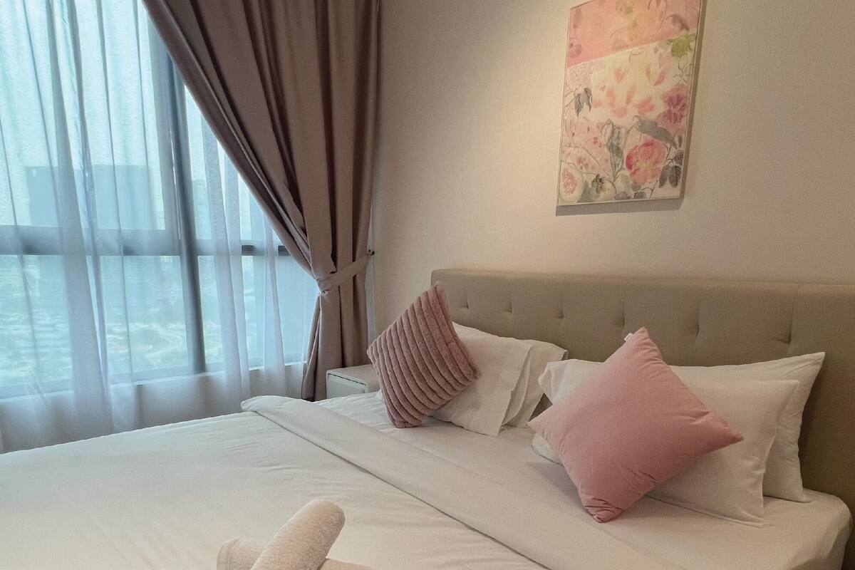 A hotel room with a large bed, a headboard, and a window with curtains.