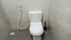 Un inodoro con función de bidé en un baño con paredes y suelo de baldosas.